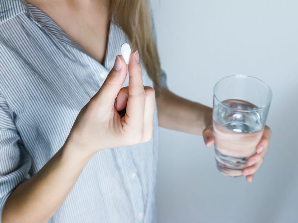girl holding a medicine and a glass of water